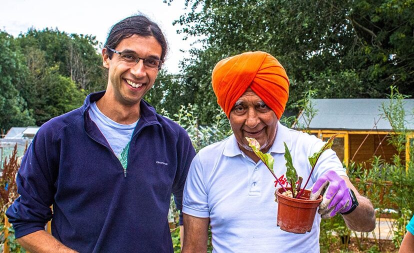 Two men and a woman from Alive posing with a plant