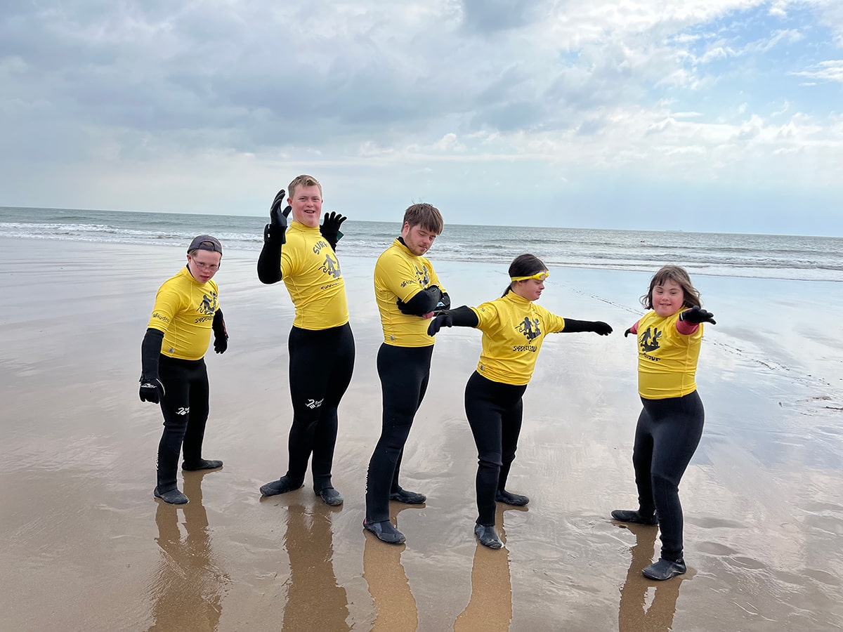 Five children posing on the beach in wetsuits