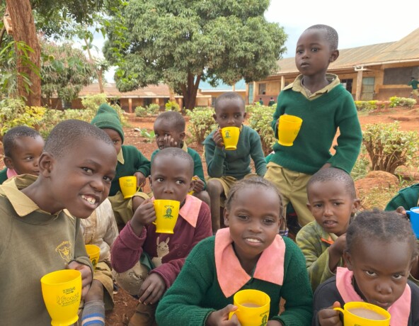 School children with breakfast club mugs of porridge.