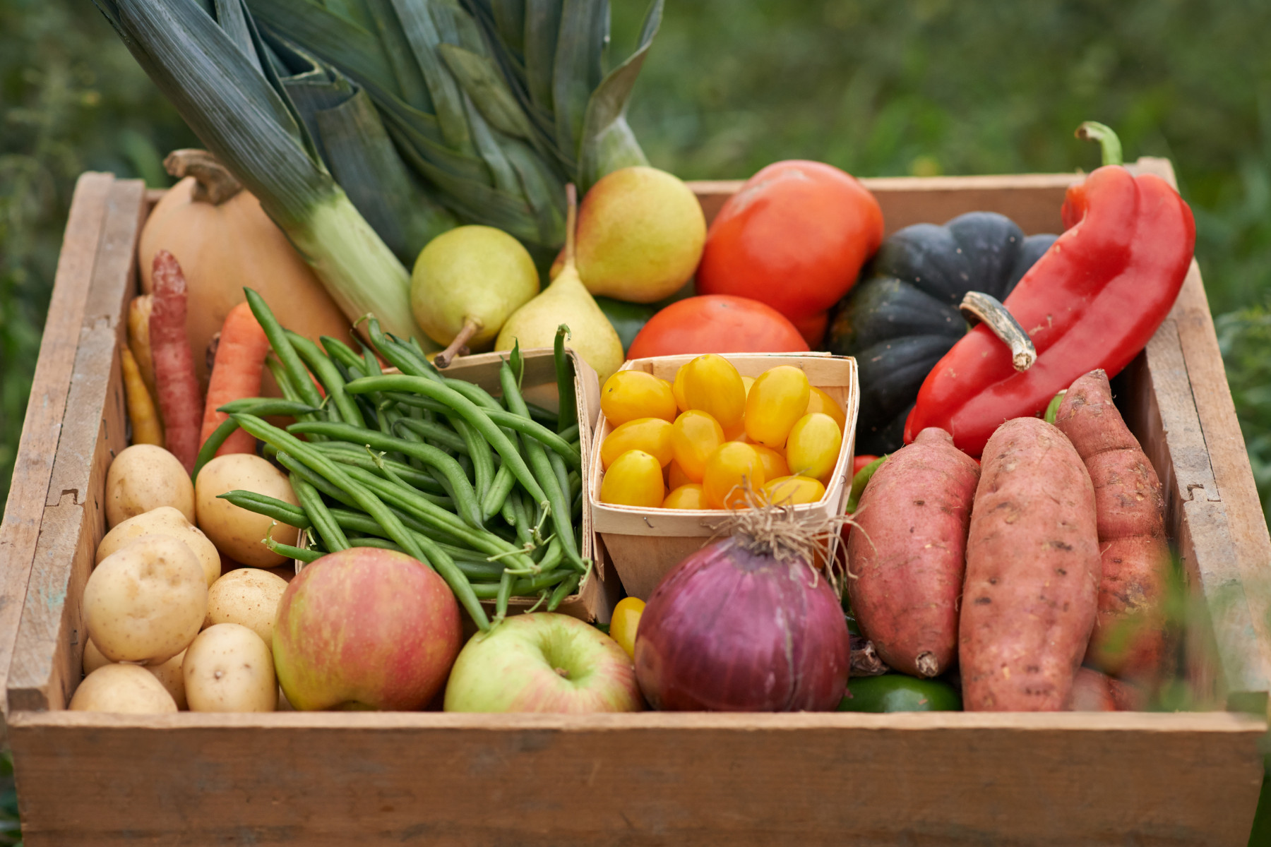 Wooden tray of farm produce. Apples, beans and potatoes